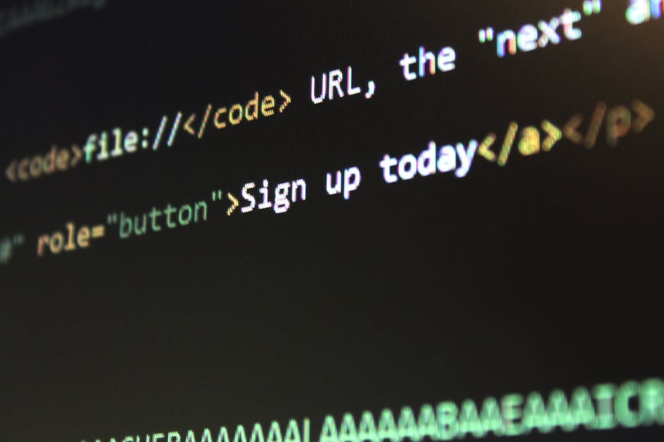 Close-up image of a computer screen displaying lines of code with syntax highlighting, including HTML tags and attributes in various colors such as yellow, orange, green, and white. The code appears t